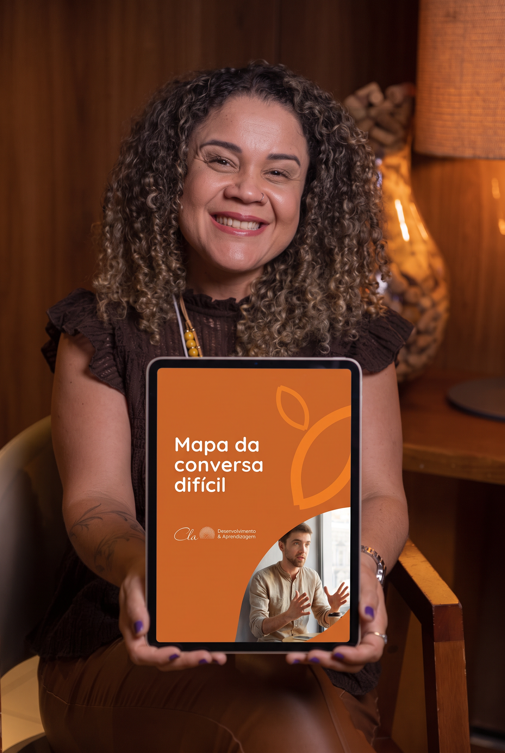 Clarice Sousa segurando um tablet que mostra a capa do Mapa para Conversas Difíceis
